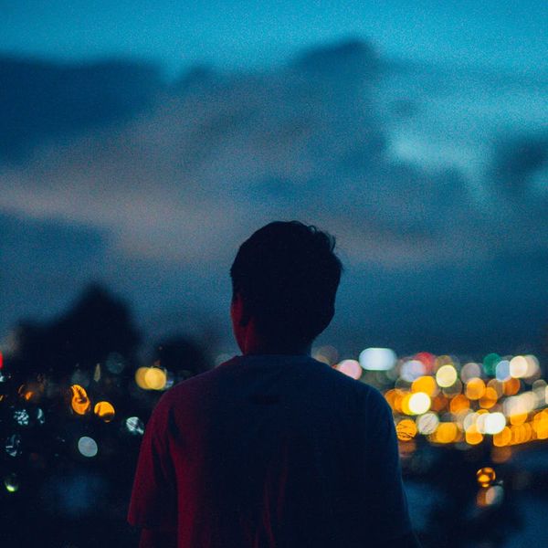 Person meditating peacefully, silhouette against a calm, dark background.