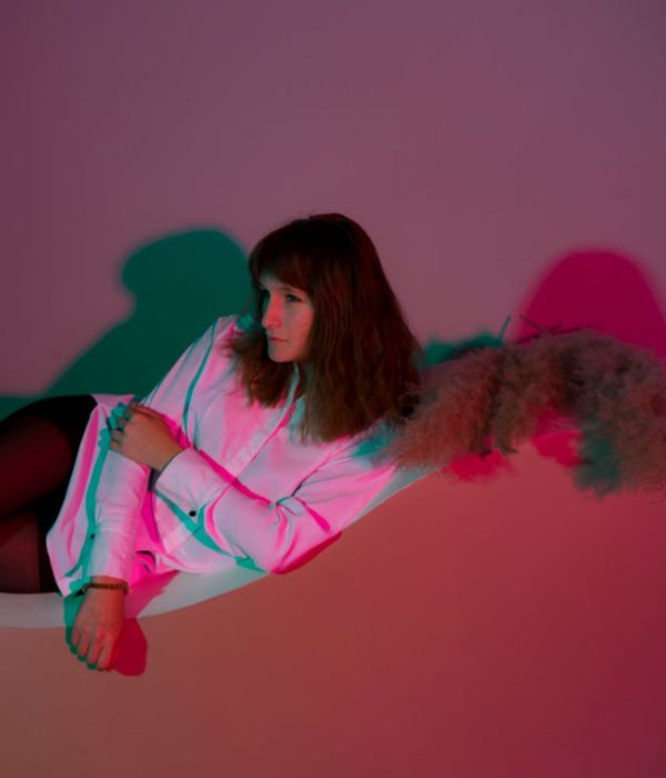Woman performing a calm yoga pose in a dark studio with lime green light.